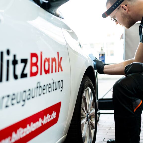 blitzblank-fahrzeugaufbereitung-mitarbeiter-poliert-auto Eine Person wäscht ein weißes Auto