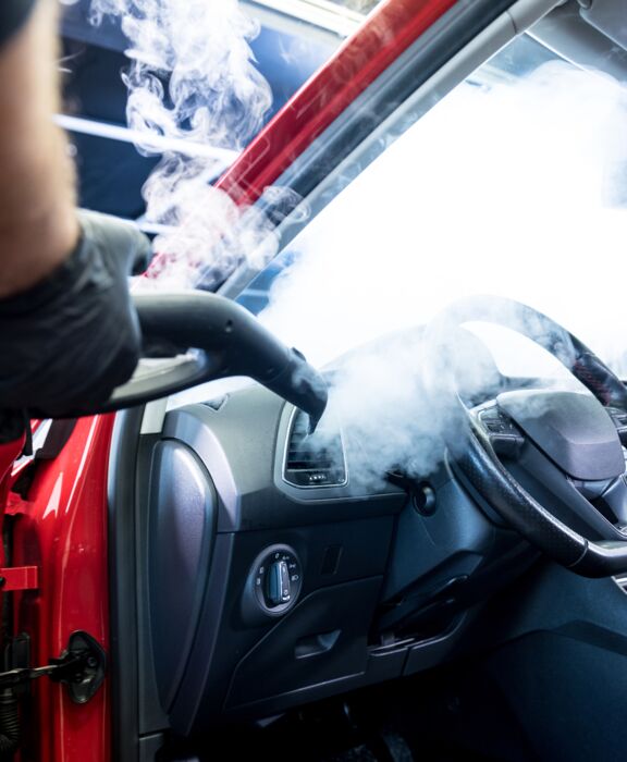 Eine Person saugt Dreck aus den Innenraum eines Autos