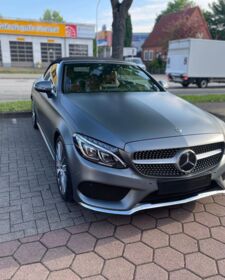 Ein mattgrauer Mercedes Benz C Cabrio in designo Mountaingrau steht auf einem Parkplatz