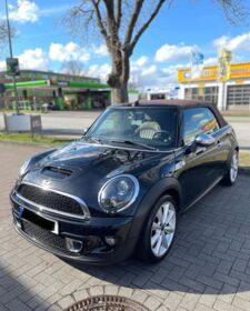 Ein schwarzer Mini Cooper Cabrio steht auf einem Parkplatz