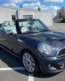 Ein dunkelgrauer Mini Cooper S Cabrio steht auf einem Parkplatz