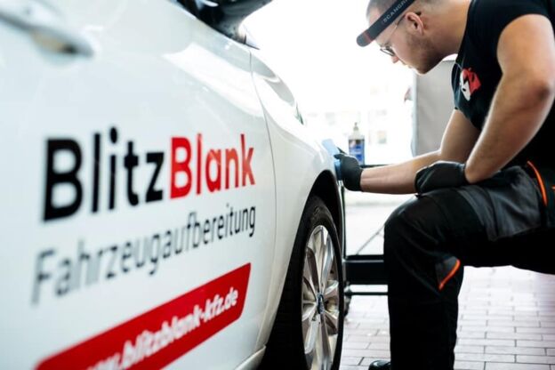 Mitarbeiter wischt einen weißen BlitzBlank Firmenwagen ab