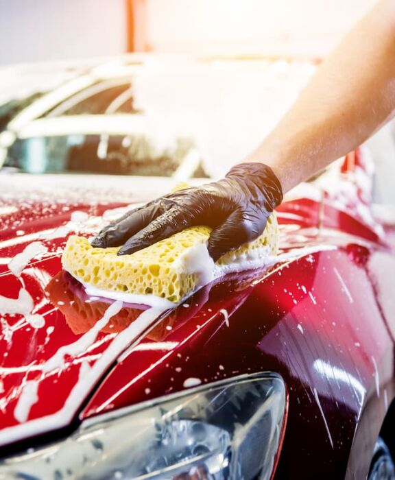 Mann wäscht mit einem Schwamm ein Auto