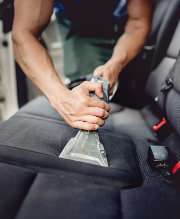 Eine Person saugt Dreck aus den Innenraum eines Autos